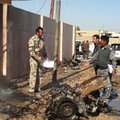 Iraqi security forces inspect the scene of a car bomb attack in front of a government compound in Ra...