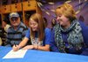 Sara Wilson, center, signs a letter of intent Wednesday to play softball for Northeastern Oklahoma A&M College in Miami, Okla., alongside her parents, Billy and Teresa Wilson, during a ceremony at the Fayetteville High softball complex.