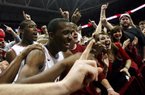 Arkansas players BJ Young (foreground) and Devonta Abron celebrate with fans after the Razorbacks held on to beat No. 20 Michigan 66-64 at Walton Arena in Fayetteville on Saturday. The Razorbacks led by 20 points in the first half but won only after Michigan’s Trey Burke missed a three-point shot at the buzzer. 