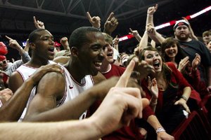 Arkansas players BJ Young (foreground) and Devonta Abron celebrate with fans after the Razorbacks held on to beat No. 20 Michigan 66-64 at Walton Arena in Fayetteville on Saturday. The Razorbacks led by 20 points in the first half but won only after Michigan’s Trey Burke missed a three-point shot at the buzzer.