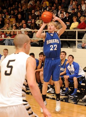 Rogers’ Collin Jones, right, attempts a 3-pointer against Bentonville at Tiger Arena in Bentonville on Friday.
