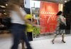 Shoppers walk past a clearance sign at the New York & Company outlet store at the Dolphin Mall in Miami, in this November photo. Consumer spending was flat in December while incomes rose by the largest amount in nine months. 
