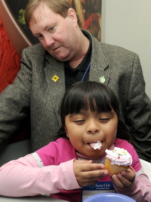 Jaquelin Troncoso, an Eastside first-grader, taste tests a cupcake with bubblegum flavored frosting in the sensory testing lab at the Sam’s Club Home Office in Bentonville on Monday. Helping Jaquelin with the test was Sam’s Club bakery buyer Paul Tichenor. Jaquelin was with a group of students from Eastside Elementary School in Rogers and Elm Tree Elementary School in Bentonville who were given a tour of the home office labs and kitchen facilities.