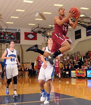 Chasen Williamson, Springdale High, right, takes the ball to the basket in front of Rogers High’s Josh Anderson during the game Tuesday at Rogers High School.