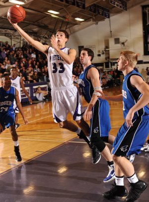 WHEN ’DOGS FLY Caleb Waitsman, Fayetteville junior forward, scores past Rogers senior post Nathan Musso, center, Friday during the first half at Fayetteville High.
