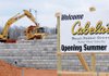 A sign displays the opening date of a new store Tuesday as construction crews work at the Cabela’s construction site on Promenade Boulevard in Rogers.
