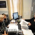 Clerk Lisa Zweimueller, right, goes over utility bills and financial statements Wednesday with Eldon...