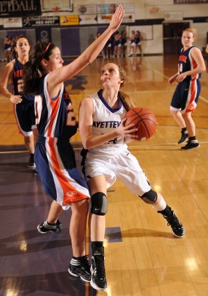 Sarah Smith, center, a Fayetteville junior guard, makes a move to the basket as Rogers Heritage sophomore guard Gina Britton, left, defends Tuesday at Fayetteville High.