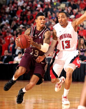 UALR guard Chuck Guy (left) drives inside past Louisiana-Lafayette guard Alan-Michael Thompson during Thursday’s game in Lafayette, La. 