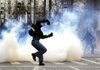 A protester throws a stone at riot police during clashes Friday in central Athens. 