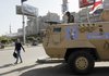 An Egyptian man passes by an army patrol with a soldier on top of an armored vehicle flying the national flag and a sticker on the body with Arabic that reads "the army and the people are one hand," during a general strike in Cairo, Egypt Saturday, Feb. 11, 2012. Egypt's military rulers have warned that the country faces conspiracies that seek to topple the state and spread chaos, in a message intended to undermine activists who plan to mark the anniversary of President Hosni Mubarak's overthrow with anti-army protests. 