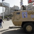 An Egyptian man passes by an army patrol with a soldier on top of an armored vehicle flying the nati...