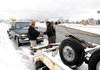 Motorist David Castaneda, left, pays Tony Salkill from Bentonville Towing for pulling Castaneda’s pickup out of the ditch near the southbound on-ramp at Exit 88 on U.S. 71 in Bentonville on Monday. Castandea said he slid off the highway but was uninjured. Salkill left minutes later to answer another towing call. The National Weather Service forecast calls for a high today near 44 degrees.