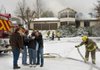 The owners of a home on Hickory Lane in Hickory Creek are consoled Monday as they watch firefighters from Hickory Creek, Nob Hill and Pleasure Heights work to extinguish a fire that has engulfed their home. Homeowner Robert Fenton, second from the left, is a former volunteer fire chief at Hickory Creek. Fenton and his wife weren’t home when the fire started. The home was heavily damaged.