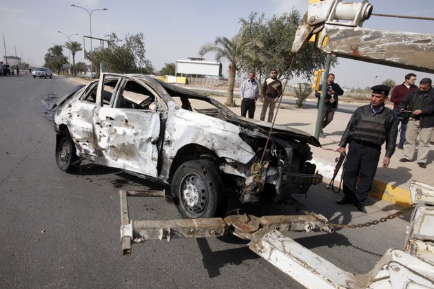 security-forces-prepare-to-tow-away-a-destroyed-car-after-a-car-bomb-attack-outside-the-fortified-academy-near-the-interior-ministry-headquarters-in-baghdad-iraq-sunday-feb-19-2012-a-suicide-bomber-detonated-his-car-as-a-group-of-police-recruits-left-their-academy-in-baghdad-killing-and-wounding-scores-of-people-police-said