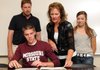 Brik Brauburger, a Bentonville senior, gets help from his mother, Theresa, while signing his letter of intent on Friday at Bentonville High School. Brauburger will play golf for Missouri State University next year.