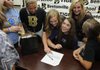 Ali Robinson, seated, is surrounded by friends and classmates Wednesday after signing a letter of intent to play golf at Ouachita Baptist University during a ceremony at the Tiger Athletic Complex in Bentonville.
