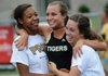 Asia Patterson, left, and Sarah Galloway, right, hug teammate Brittani Reagan on Thursday at Mountie Stadium in Rogers during the Class 7A State Track meet after Reagan won the triple jump event. 
