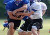 Max Harrell, right, of Rogers High fakes a handoff to Zach Wary on Wednesday during spring practice behind Mountie Stadium in Rogers. 