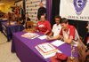 Aidan Swain, right, and Tevin Whitney, both Fayetteville senior track athletes, smile as they prepare to sign national letters of intent to run for the University of Arkansas during a ceremony at Fayetteville High School on Tuesday. With Whitney is his mother, Kristina Andazola, left, and with Swain are his parents David Swain and Jenni Taylor Swain. Also signing letters of intent at the ceremony were Macy Manning, who signed with Princeton; Will Montgomery, who signed with Rhodes College; and Nathan Varady, who signed with Massachusetts Institute of Technology.