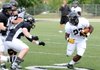 Tearris Wallace, right, looks for an opening through the defensive line Friday during the Bentonville Tigers scrimmage at Tiger Stadium in Bentonville.