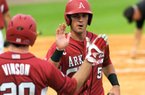 Arkansas third baseman Matt Reynolds (5) is congratulated by teammate Matt Vinson on Tuesday after scoring one of three first-inning runs in the Razorbacks’ 6-5, 10-inning victory over Louisiana Tech at Dickey-Stephens Park in North Little Rock. 
