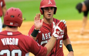 Arkansas third baseman Matt Reynolds (5) is congratulated by teammate Matt Vinson on Tuesday after scoring one of three first-inning runs in the Razorbacks’ 6-5, 10-inning victory over Louisiana Tech at Dickey-Stephens Park in North Little Rock. 