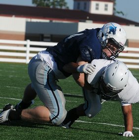 Peyton Squires, left, a Springdale Har-Ber linebacker, tackles wide receiver Miguel Salgado during practice May 10 at the school’s practice field.