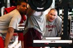 Razorback football Head Strength and Conditioning Coach Jason Veltkamp (R) gives encouragement to player Khiry Battle as he does leg exercises Thursday, March 5, 2009 in the weight room at the indoor practice facility on the University of Arkansas campus in Fayetteville. Spotting is Freddy Burton (L).