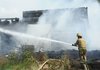 Capt. Willie Watts fights a fire that destroyed a structure Thursday at 11199 W. Arkansas 156 in West Fork. Farmington, West Fork, Prairie Grove and Strickler fire departments responded to the incident.