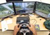 Computer screens turn a tabletop into a simulated car in motion, giving a driver’s-eye view of the ever-changing highway. 