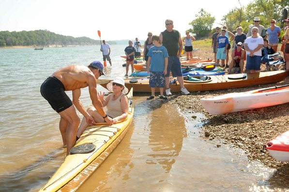 A volunteer helps Herbert show one way to get seated in a kayak.