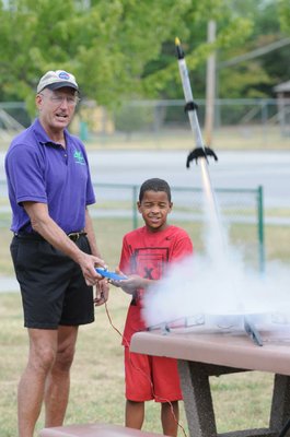 
                           Stephen Cox with Mad Science of Arkansas finishes counting down as Kolby Bowman pushes the button and watches the Estes Rockets he made take off.
