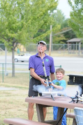 
                           Stephen Cox with Mad Science of Arkansas finishes counting down as Maurice Olvera pushes the button and watches the Estes Rockets he made take off.