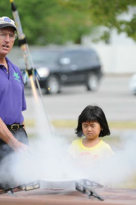 
                           Stephen Cox with Mad Science of Arkansas finishes counting down as Maily Pham pushes the button and watches the Estes Rockets she made take off.