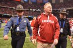 Former University of Arkansas Coach Bobby Petrino leaves the field escorted by Capt. Lance King of the Arkansas State Police after the 2011 Allstate Sugar Bowl in New Orleans. The state police agency is setting a strict policy for troopers who provide security at athletic events. 
