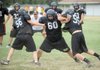 Kallin Stokes, center, a West Fork defensive lineman, fights through the blocks of Carl Lant, left, and Jake Jarnagan, right, during practice Friday at West Fork.