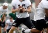 Reece Dollins, Bentonville High School quarterback, drops back to pass on Aug. 8 during practice inside Tiger Stadium.