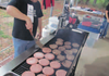 Dennis Huston takes pride in manning the large grill cooking Blackhawk Burgers under the covered pavilion the Pea Ridge Booster Club uses.
