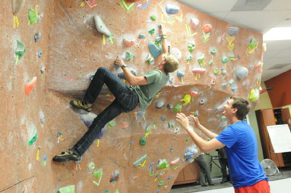 
                           Connor Wilson tests his climbing skills on a bouldering wall while Jacob Martin spots for him on Tuesday at the University of Arkansas Outdoor Connection Center.  