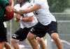 Bentonville offensive lineman Trevor Foster (right) and many of his teammates began practicing this season with new protective helmet covers, which are designed to reduce the impact from helmet-to-helmet contact.