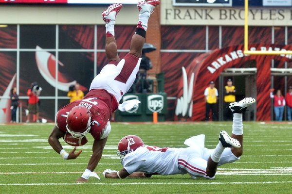Arkansas’ Knile Davis loses the ball after being upended by Alabama’s Deion Belue during Saturday’s game at Reynolds Razorback Stadium. Davis was ruled down on the field, but a review overturned the call, giving Alabama the ball and resulting in Arkansas’ third lost fumble. The Razorbacks turned the ball over five times in the 52-0 loss, the worst Fayetteville setback in 93 years. Video available at Arkansasonline.com/videos 