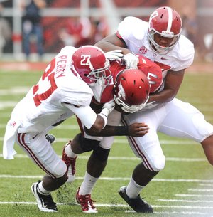 Arkansas quarterback Brandon Mitchell (17) is tackled by Alabama defensive back Nick Perry (27) and linebacker Xzavier Dickson during the first quarter. Arkansas was held to 137 yards of total offense during Saturday’s game. 