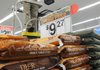 Employee Ron Rossicoe works on a display over sacks of deer corn Tuesday at the Wal-Mart on Walnut Street in Rogers. 