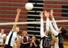Mariah King, left, Springdale High junior, spikes the ball Tuesday over Siloam Springs junior Lauren Cook and sophomore Baily Cameron during the third set at Bulldog Gymnasium in Springdale.