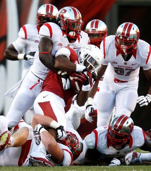 Arkansas running back Knile Davis (center) is stopped by a host of Rutgers defenders during the first quarter Saturday. With its running game shut down, Arkansas relied on quarterback Tyler Wilson, who completed 20 of 40 passes for 419 yards and 3 touchdowns, but a key fourth-quarter interception in the end zone ensured Rutgers’ victory. 