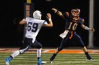 Josh Qualls, right, Rogers Heritage, passes the ball Friday over Chase Bowers of Springdale Har-Ber at Gates Stadium in Rogers. 