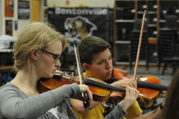 
                           Heidi Dray, left, and Ben Walter play in the violin section of the Bentonville High School orchestra during a practice.
