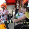Jake Egberts, left, disguised as a killer clown, moves in for a candy treat Wednesday from queen bee...