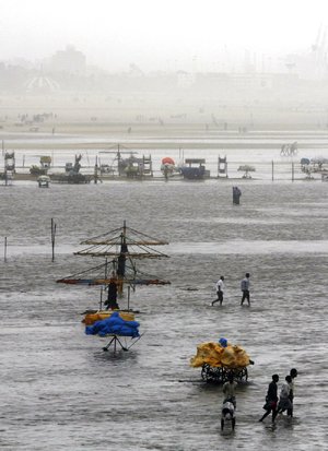 People walk on the beach in Chennai, India, after it was flooded Wednesday by a tropical storm.